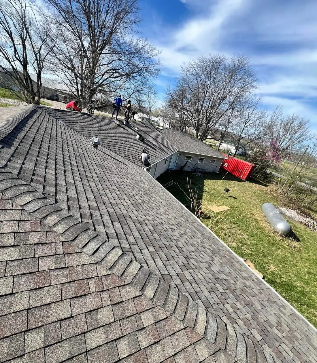 Full Roof roofers working along the ridge of a new shingle roof