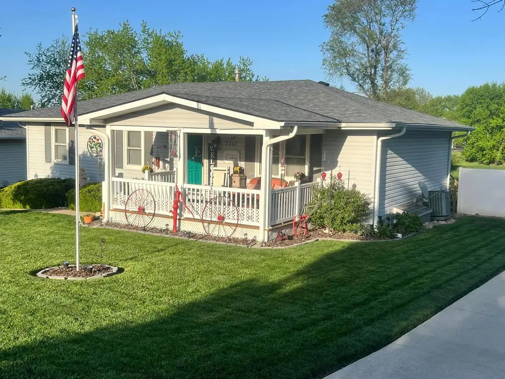 Ranch house with a front porch, flag pole and a new shingle roof