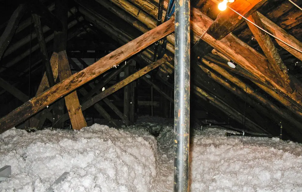 Attic floor covered deep in loose-fill insulation under old rafters