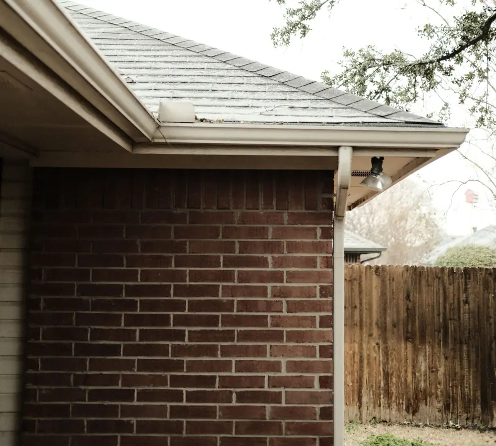 Fascia, gutter, downspout and vented soffit at the corner of a brick house