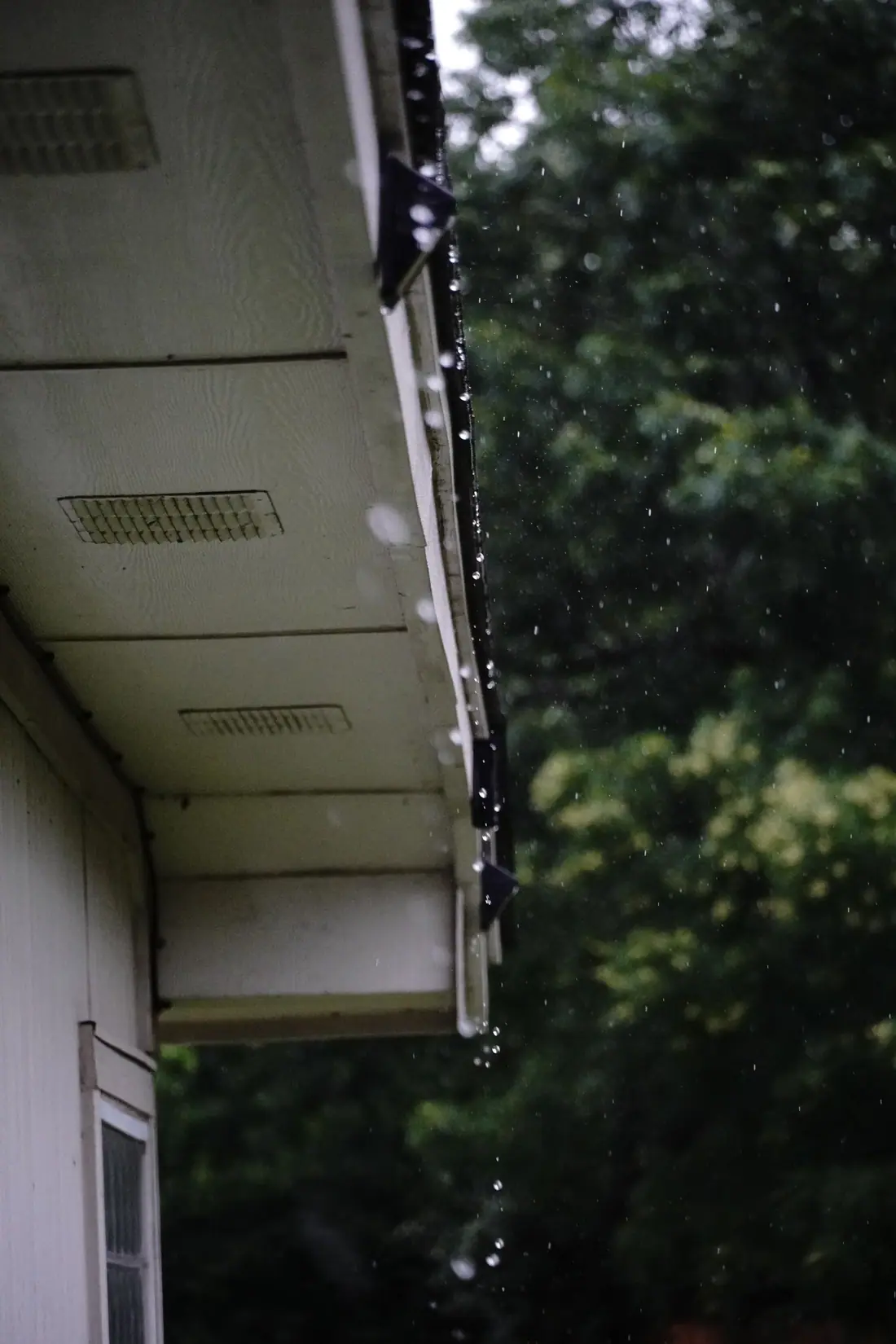 Vented soffit, fascia and gutter at a roof eave in the rain