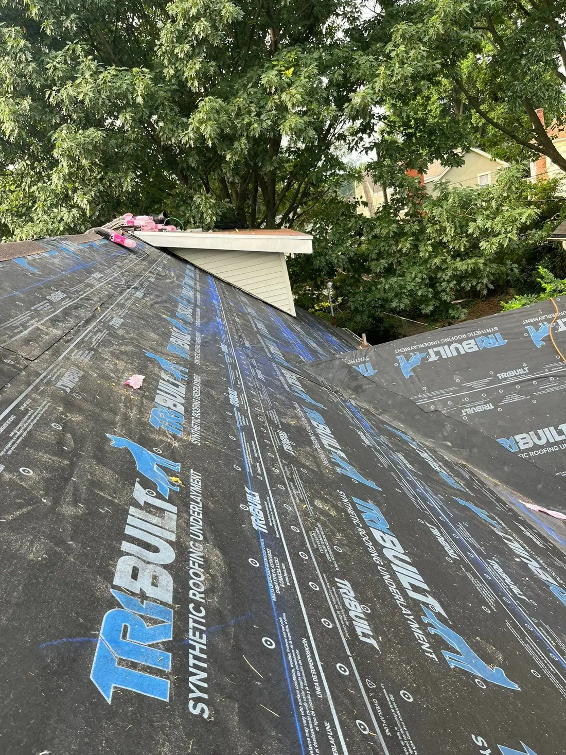 Synthetic roofing underlayment rolled out over a new roof deck