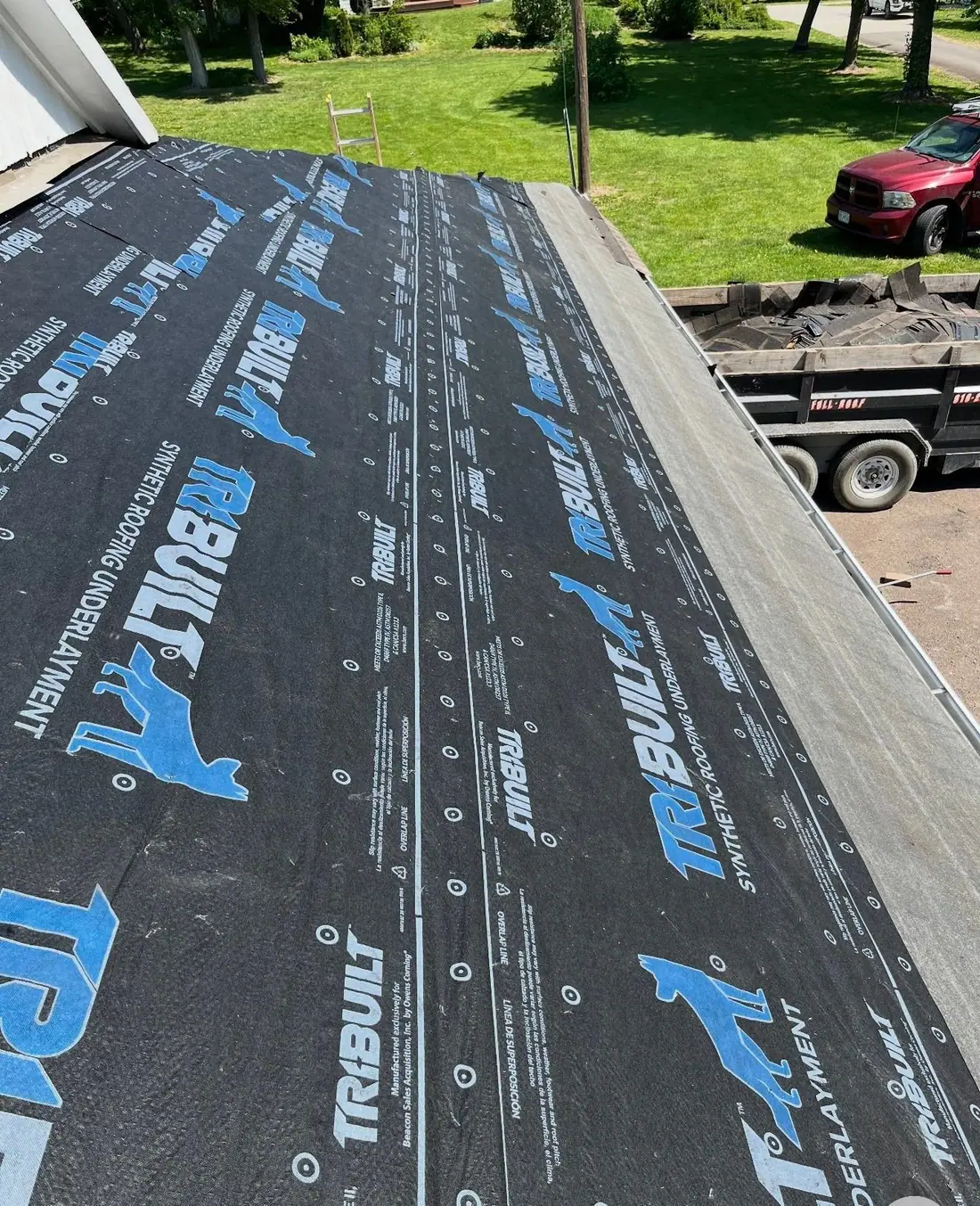 Synthetic underlayment over the deck with the dump trailer below during a tear-off