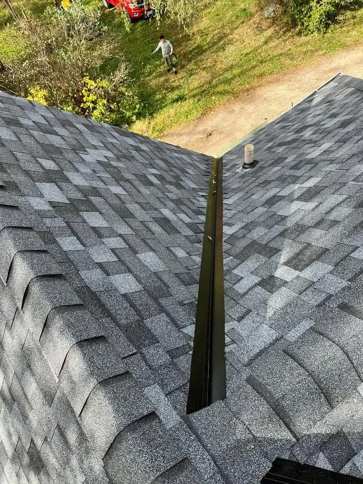 Roof valley lined with metal flashing between new shingles